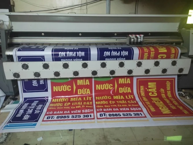 Một tấm bạt sinh thái được in màu sắc tươi sáng, hiển thị thông điệp quảng cáo rõ ràng, treo tại khu vực ngoài trời như hội chợ, sự kiện hoặc mặt tiền cửa hàng. 